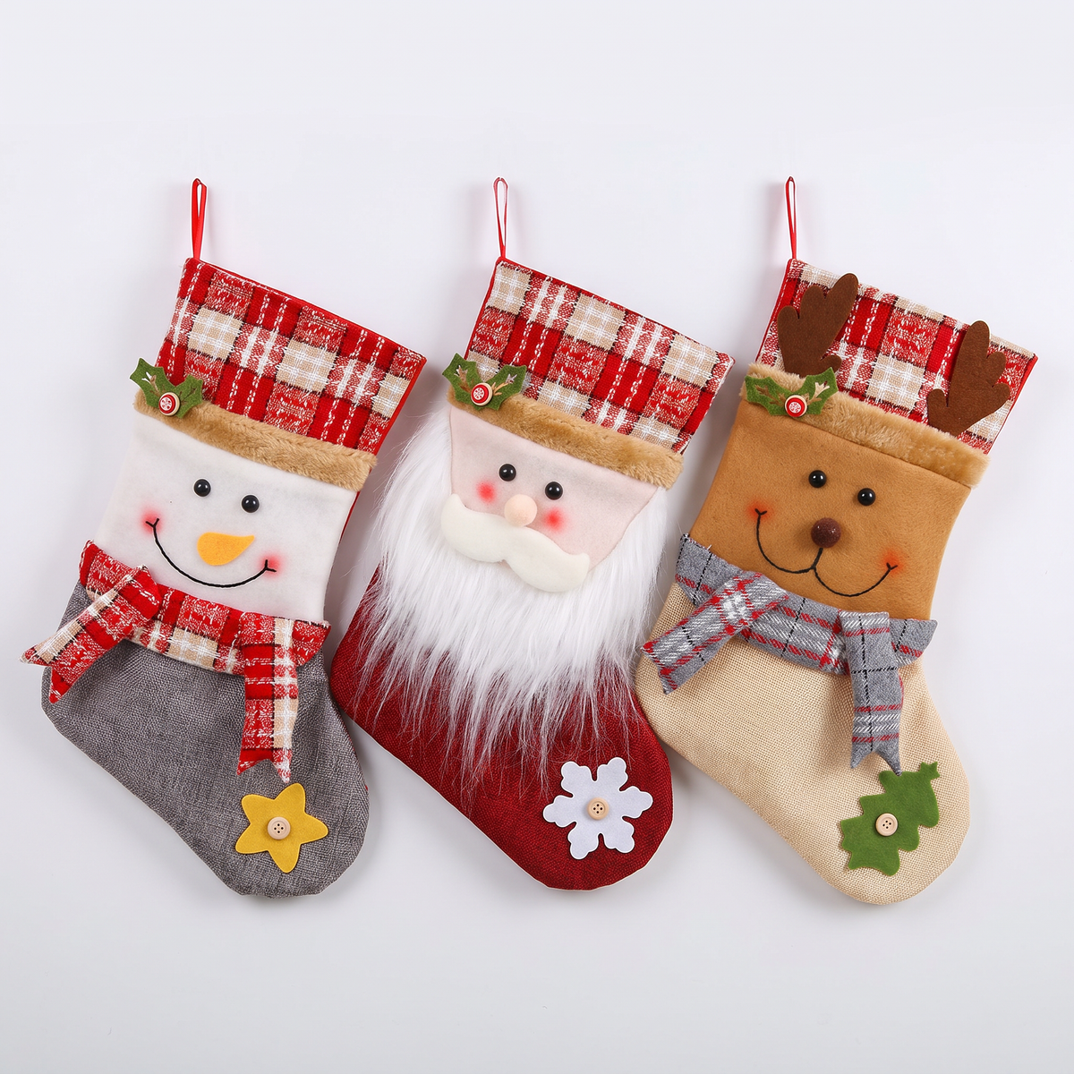 Tres botas navideñas de peluche para colgar: muñeco de nieve, Viejo Pascuero y reno, fondo blanco